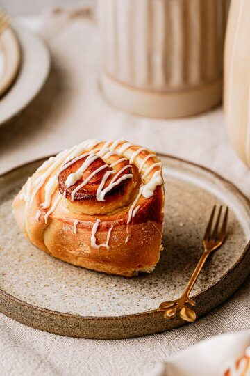 Glasierte Eierlikörschnecken serviert auf Steingutteller mit goldener Gabel auf gedecktem Tisch.